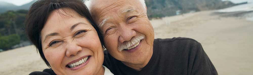 older couple smiling, at the beach