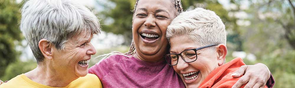 three older ladies laughing and hugging