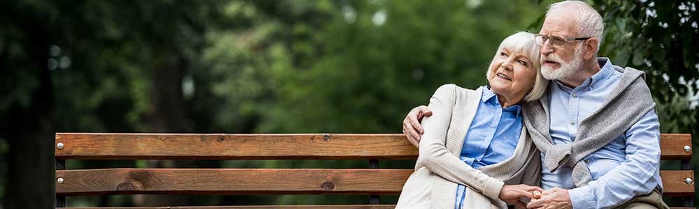 older couple embracing and siting on a bench in a park