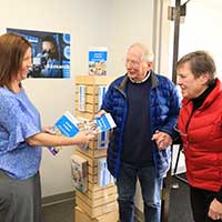 APDA staff handing an older couple a brochure