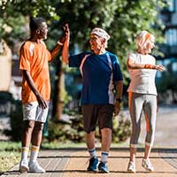 four seniors walking in a park and giving a high five