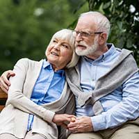 older couple embracing and siting on a bench in a park